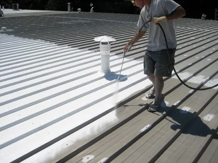 Construction workers applying coating to roof