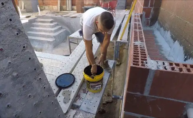 Worker applying coating to concrete planter box